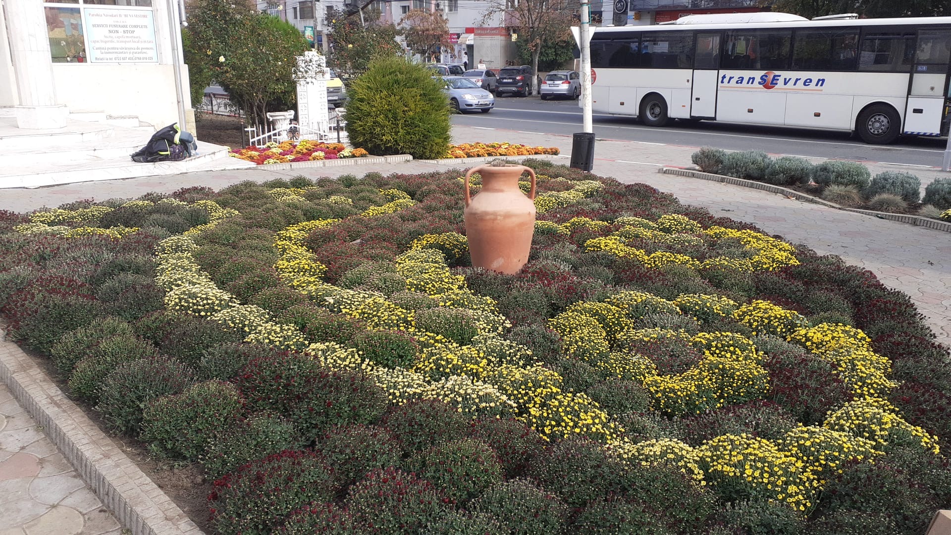 Rond floral cu vas decorativ lângă stația de autobuz